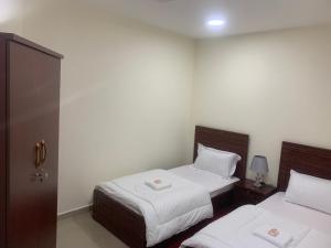 Habitación de hotel con 2 camas con sábanas blancas en Family rooms with beach view يستضيف مكان الإقامة هذا العائلات فقط, en Ajman