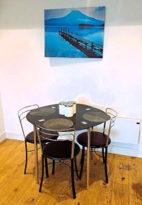 een zwarte tafel met stoelen en een schilderij aan de muur bij Paradise - Away - From - Home in Bracknell