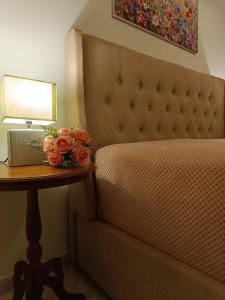 ein Bett mit einem Tisch mit einer Lampe und Blumen darauf in der Unterkunft Maria GuestHouse in Aliveri