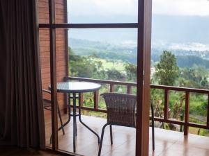 una mesa y una silla en un balcón con vistas en Catu Glamping Bedugul, en Tabanan