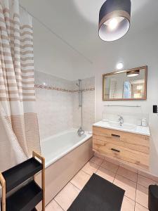 een badkamer met een bad, een wastafel en een spiegel bij Appart chaleureux et calme près de PARIS et MÉTRO in Asnières-sur-Seine