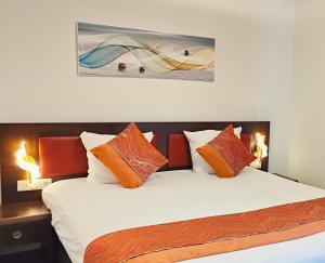 CN-Hotel في آرنم: غرفة نوم مع سرير مع وسائد برتقالية وبيضاء
