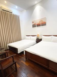 een hotelkamer met 2 bedden en een stoel bij Ngọc Toàn Hotel in Dong Hoi