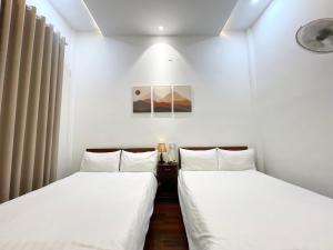 twee bedden in een kamer met witte muren bij Ngọc Toàn Hotel in Dong Hoi