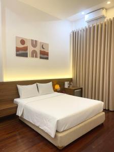 een slaapkamer met een groot wit bed en gordijnen bij Ngọc Toàn Hotel in Dong Hoi