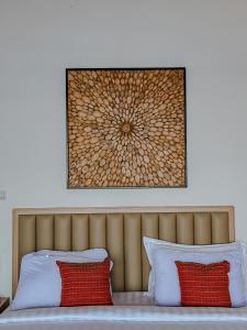 a picture above a bed with two red pillows at Morika Villa in Rua