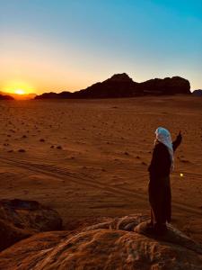 a woman standing in the desert at sunset at Wadi Rum Bedouin Heart Camp in Wadi Rum