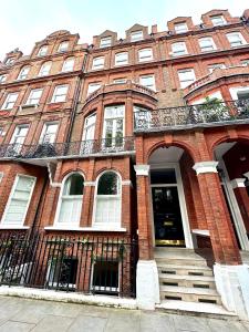 een rood bakstenen gebouw met een trap ervoor bij 2 Bedroom Apartment in Central London South Kensington in Londen