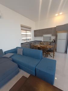a living room with a blue couch and a kitchen at Villa rotana airport road in Al Qasţal