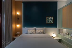 a bedroom with a large white bed with a blue wall at Bare Hyphen - Bare Boutique Stays in Ho Chi Minh City