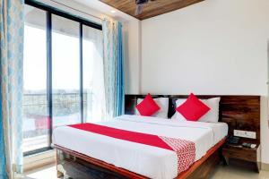 a bedroom with a bed with red pillows and a window at OYO Comfort lodging and boarding in Kalyan