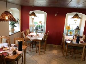 a dining room with tables and chairs and two windows at Pension Scherzer in Ohorn