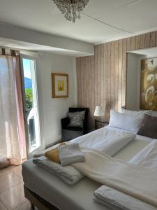 a bedroom with a large bed with a chair and a window at Pensione Olanda in Locarno