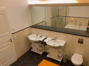a bathroom with two sinks and a toilet and a mirror at Stilvoller Urlaub im Zentrum LEs in Leipzig
