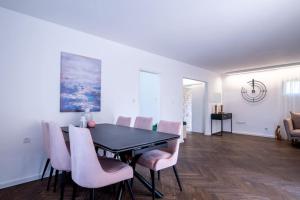a dining room with a black table and pink chairs at Stylish 4BR Villa - Herzliya Pituah in Herzelia 