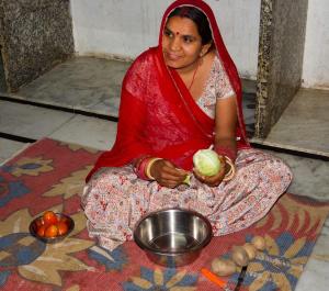 una mujer sentada en el suelo con un tazón de comida en Pukhraj Garh- A Heritage Homestay, en Jodhpur