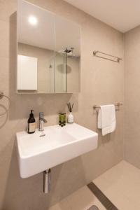 y baño con lavabo blanco y ducha. en 2BDR Brand New Apt - Moments from RNSH & St Leonards en Sídney