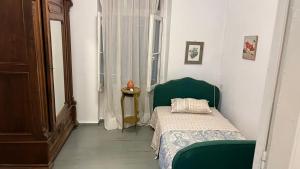 a small bedroom with a green bed and a window at Traditional Detached House in Spetses