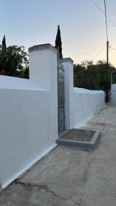 a white fence with a gate and a white wall at Traditional Detached House in Spetses