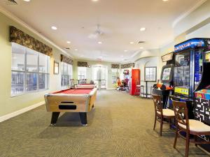 uma sala de jogos com uma mesa de bilhar e máquinas de jogos em Archfeld Villa 2582 em Orlando