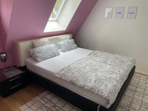 a bed in a bedroom with a purple wall at City Wohnung mit Gartenblick und Dachterrasse in Verden