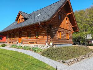 a large wooden house with a black roof at Apartmány u vlčích jam in Petrovice u Susice