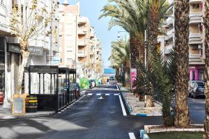 una strada vuota con palme ed edifici di Casa Encanto Torrevieja a Torrevieja