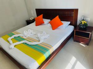 a bed with orange and colorful pillows on it at Lafala Hotel & Service Apartment in Colombo