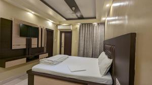 um quarto com uma cama e uma televisão na parede em Hotel Binapani em Tarapith