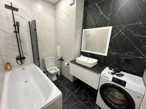 a bathroom with a sink and a washing machine at 1-комнатная квартира, 43.7 м², 8/9 этаж посуточно in Zhumysker