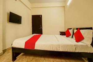 um quarto com uma cama com almofadas vermelhas e uma televisão em OYO ROYAL HAVEN em Hyderabad