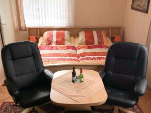 twee stoelen en een tafel in een kamer met een bed bij Holiday homes for two people with a swimming pool in the Ore Mountains in Pockau