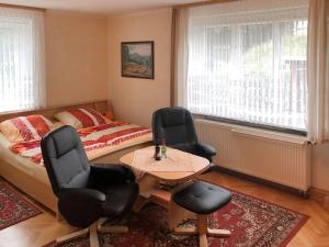 a bedroom with a bed and two chairs and a table at Holiday homes for two people with a swimming pool in the Ore Mountains in Pockau