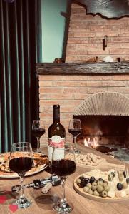 uma mesa com copos de vinho e uma lareira em Cottage GarShemo Kazbegi em Kazbegi