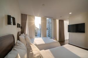 Cette chambre comprend 2 lits et une télévision à écran plat. dans l'établissement Hato Saigon Hotel & Rooftop, à Hô-Chi-Minh-Ville