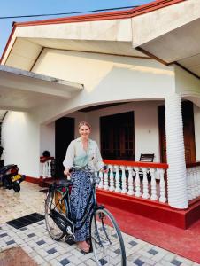 a man standing with a bike in front of a house at Ceylon Glory Hostel in Negombo