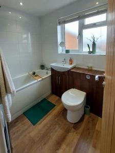 La salle de bains est pourvue de toilettes, d'une baignoire et d'un lavabo. dans l'établissement Village Home -Syston, Leicestershire, à Syston
