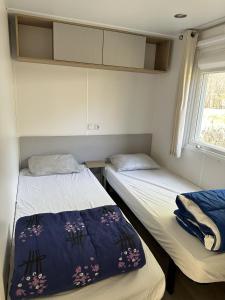 2 Betten in einem kleinen Zimmer mit Fenster in der Unterkunft Camping du Bourg in Digne-les-Bains