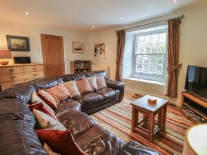 - un salon avec un canapé en cuir et une télévision dans l'établissement Argyle Cottage, à Ambleside