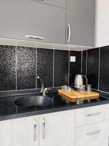 a kitchen with a sink and a black tiled wall at palmiye butik otel in Mezitli