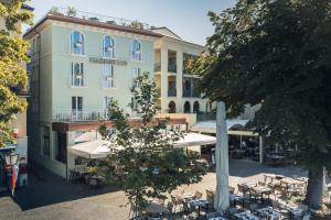 een gebouw met tafels en parasols ervoor bij Hotel Giardinetto in Garda