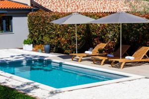 a swimming pool with two chairs and an umbrella at Garden House Rovinj in Rovinj