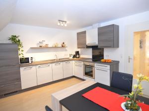 kuchnia z białymi szafkami i stołem w obiekcie Apartment near ski area in Wehrstapel in Sauerland w mieście Meschede