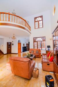 a large living room with leather furniture and a staircase at The Norfolk Heritage Airport Villa in Katunayake