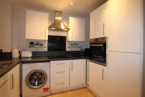 a kitchen with white cabinets and a washer at The Elm @ Short Stays in Basingstoke