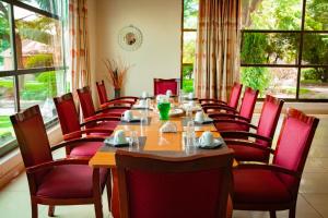 a dining room with a long table and red chairs at Fatmols City Hotel in Ndola