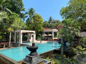 a swimming pool with a fountain in front of a house at Tusita Wellness Resort in Paktako