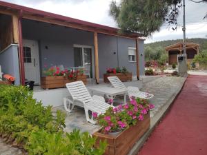 zwei Stühle und ein Tisch auf einer Terrasse mit Blumen in der Unterkunft Pefkari Bay Villas in Pefkari