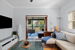a living room with a couch and a television at Relaxed Clovelly Beach Home - Parking - Cloey6 in Sydney