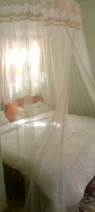 uma cama branca com dossel num quarto em Nilenian Holiday Villas em Jinja